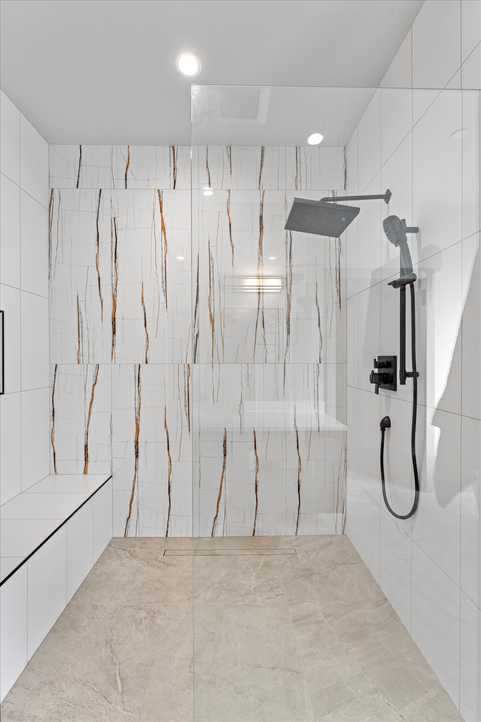 Primary bathroom shower with veined marble
